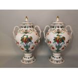 A pair of Italian style ceramic twin handled baluster urns, with lids, decorated with fruiting