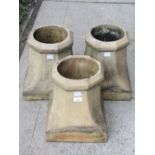 Three reclaimed buff coloured chimney pots of squat octagonal and waisted form, 35 cm high