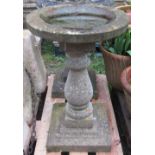 A weathered cast composition stone two sectional birdbath of circular form with baluster column