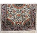 A Persian silk rug, with central floral medallion surrounded by further scrolled foliage upon a