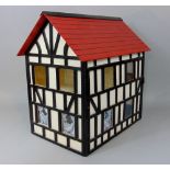 A dolls house in the form of a Tudor black and white building beneath a red tiled roof, four room