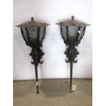 A pair of exterior iron work wall lanterns of hexagonal form with frosted glass panels and tapered