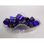 A box containing a collection of various antique blue glass liners for mustards or salts, together