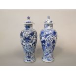 A pair of 19th century oriental blue and white vases and covers of shouldered form with painted