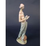 A Lladro Daisa figure of a clown standing beside a bag, 35cm tall