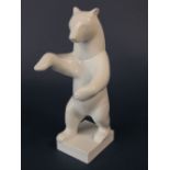 A Berlin white glazed model of a standing bear, raised on a rectangular base with blue sceptre