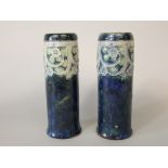 A pair of Royal Doulton vases of cylindrical form with relief moulded flower head detail on a