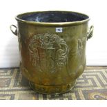 An embossed brass coal/log bin of cylindrical form with lions mask and ring handles, armorial shield