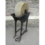 An old vintage sharpening stone /grinding wheel, hand driven, and cradled in a cast iron stand