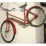 A vintage ladies bicycle with tubular frame, swept back handlebars and over painted red livery (