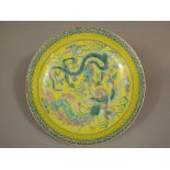 A 19th century oriental yellow ground dish with painted dragon and flaming pearl detail, with