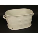 A 19th century cream glazed two handled foot bath with relief moulded banded detail, 49cm long