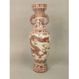 A tall oriental vase with painted puce detail of a dragon chasing a flaming pearl and with moulded