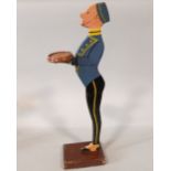 Carved and painted dumb waiter in the form of a bell boy, upon a wooden plinth base, 90cm high