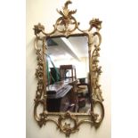 A carved and gilded wall mirror in an 18th century manner, with trailing floral detail, acanthus and