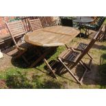 A contemporary weathered hardwood garden table of oval form with slatted top and folding x framed