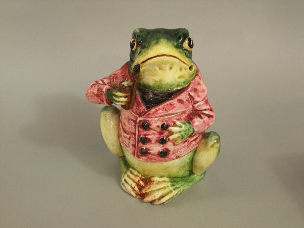 A late 19th century continental tobacco jar and cover in the form of a pipe smoking frog in a pink