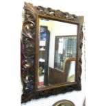 An oak framed wall mirror of rectangular form with bevelled edge plate within a carved frame with