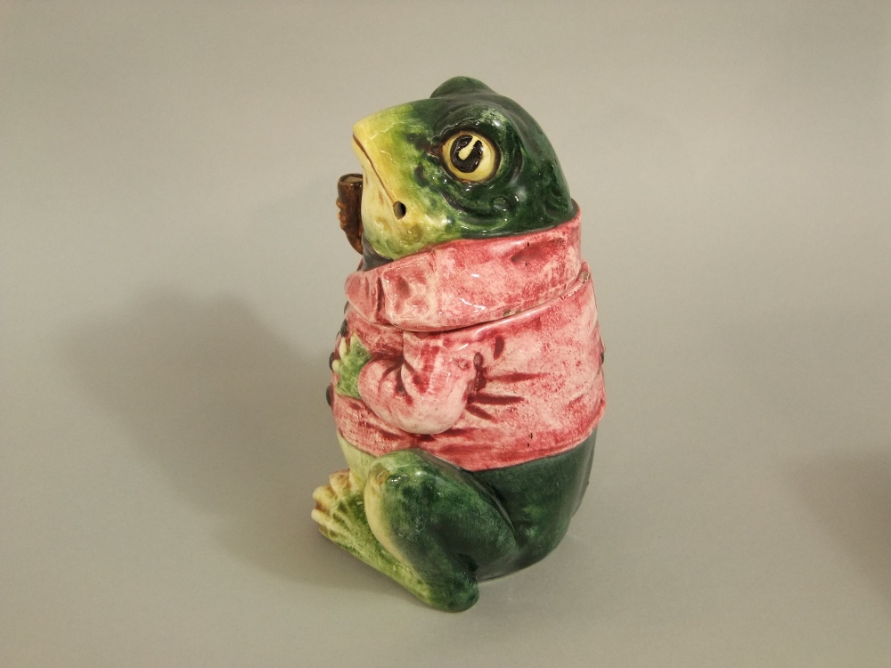 A late 19th century continental tobacco jar and cover in the form of a pipe smoking frog in a pink - Image 2 of 5