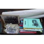 A box containing a collection of black and white topographical postcards and photographs including