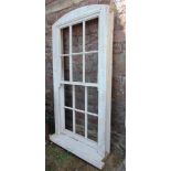 A painted bespoke pine sash window with slightly arched frame and vacant glass panels, 180 cm high x