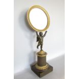 19th century bronze and gilt bronze figural mirror, the tondo glass in a darted ormolu frame, held
