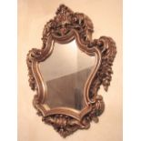 A rococo style wall mirror, the shield shaped frame with acanthus, floral and other detail, 70cm x