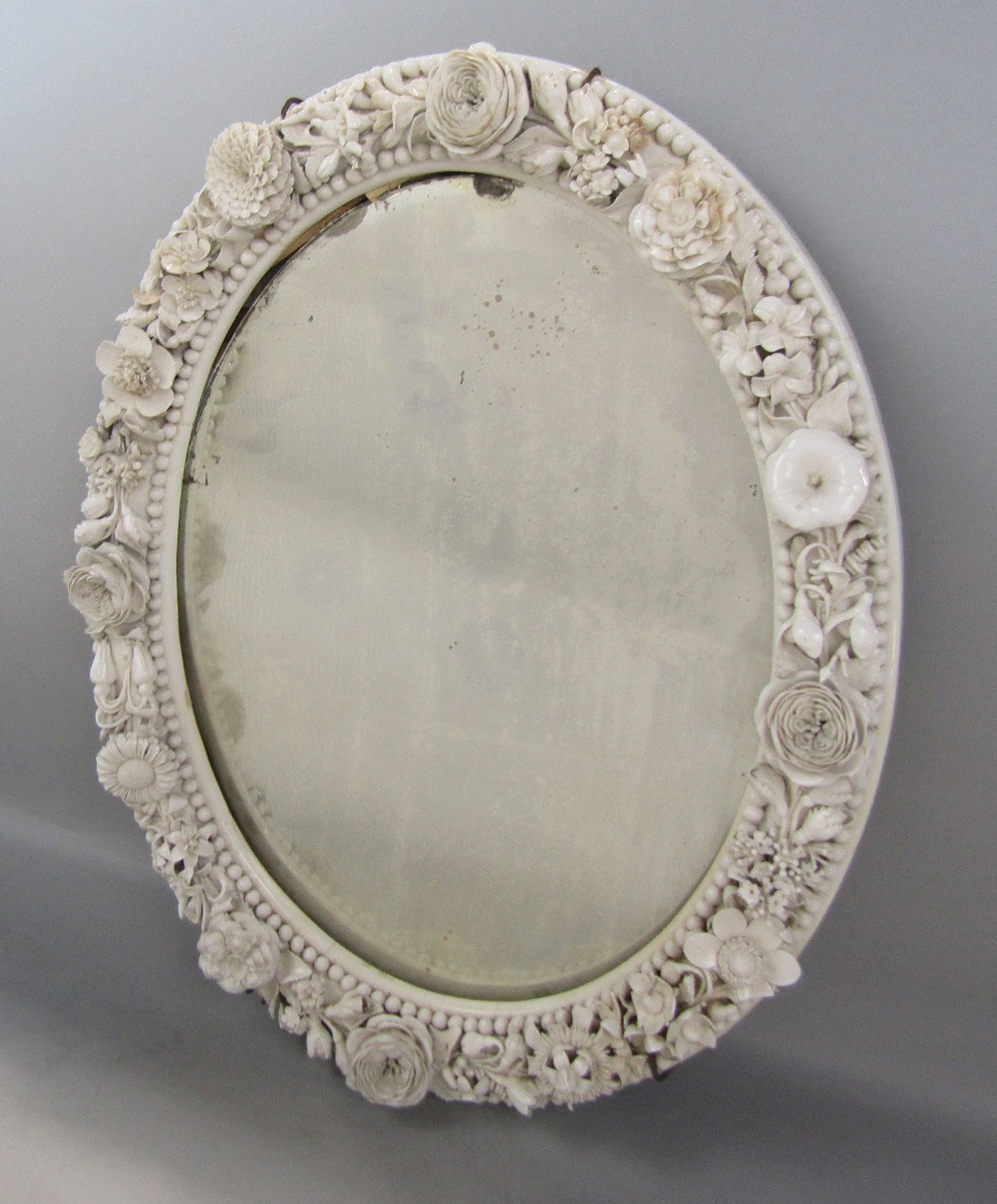 19th century blanc de chine porcelain oval wall mirror, decorated with various delicate flower work,