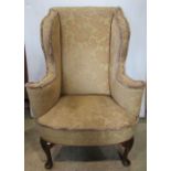 A good quality Georgian style wing armchair with shaped outline and beige ground floral patterned