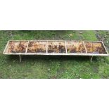 A vintage cast iron pig feeding trough of rectangular form with four rung divisions and weathered