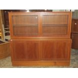 A mid 20th century teak two sectional side cupboard enclosed by two pairs of sliding panelled doors,