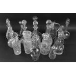 A large collection of mainly cut and etched glass decanters, together with a silver plated claret