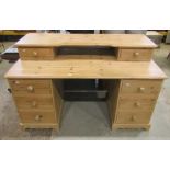 A stripped pine kneehole desk fitted with an arrangement of drawers and raised back, 140 cm wide