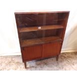 A low teak veneered side cabinet enclosed by four sliding the doors, the upper glazed revealing a