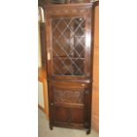 An Old English style oak freestanding corner cupboard, the lower section with carved detail, the