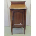 An inlaid Edwardian mahogany bedside cupboard enclosed by an arched panelled door with satinwood