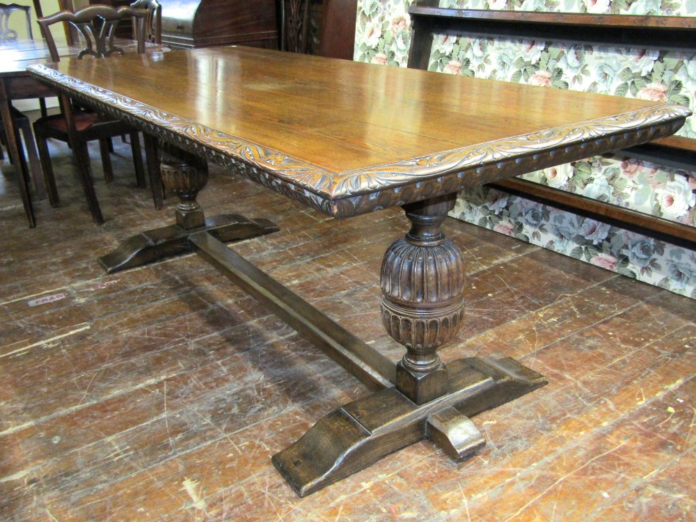 A 19th century oak refectory table, the plank top with carved borders, raised on a pair of