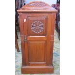 A late Victorian walnut bedside cupboard enclosed by a twin panelled door with carved flower head