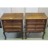 A pair of low oak three drawer bedside chests with moulded outline and scrolled cabriole forelegs