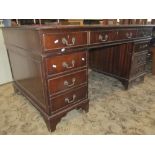 A reproduction Georgian style mahogany veneered kneehole twin pedestal writing desk with inset green