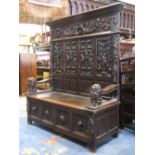 A good quality 19th century settle with box seat, high back enclosing four panels with mask, figural