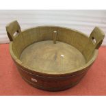 A 19th century oak dairy bowl with banded borders, cut handles and timber plug, 60 cm diameter