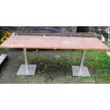 A contemporary garden table, the stained pine top of rectangular form raised on a pair of tubular