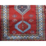 Afghan rug with central blue medallions upon a red ground, 200 x 120cm
