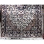 Full pile Persian rug decorated with scrolled navy blue floral decoration upon an ivory ground,