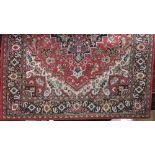 Hammadan style machine woven carpet with central navy blue floral medallion and further floral