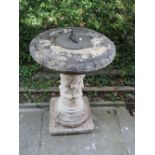 A contemporary garden sundial, the partially weathered composition stone column with trailing
