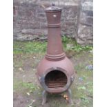 A cast iron chiminea with three shaped legs and enclosed by an oval vacant hinged door