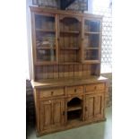 A stripped pine farmhouse kitchen dresser, the base partially enclosed by a pair of rectangular twin