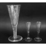A pair of antique cordial glasses on stepped circular bases together with a further over sized